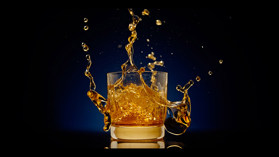 Scotch glass with gold liquid splashing