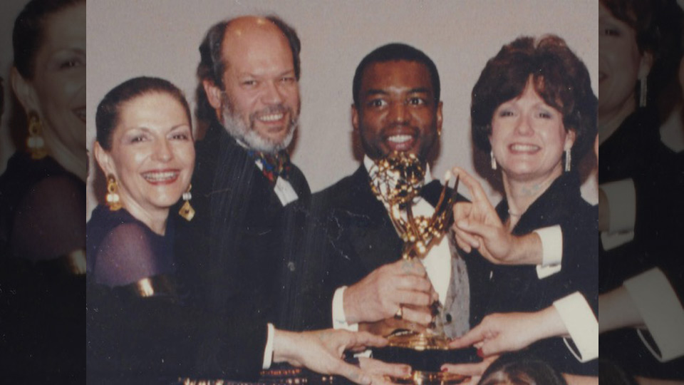 Four people hold an Emmy award