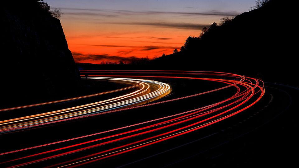 Long exposure photo of cars driving at dusk