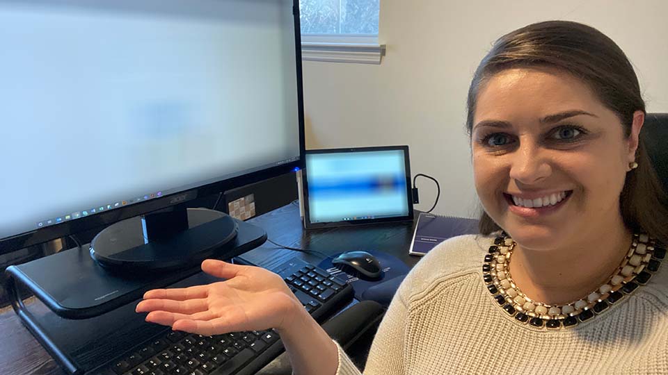 remote employee in home office with laptop, monitor, keyboard, mouse, and notebook on desk